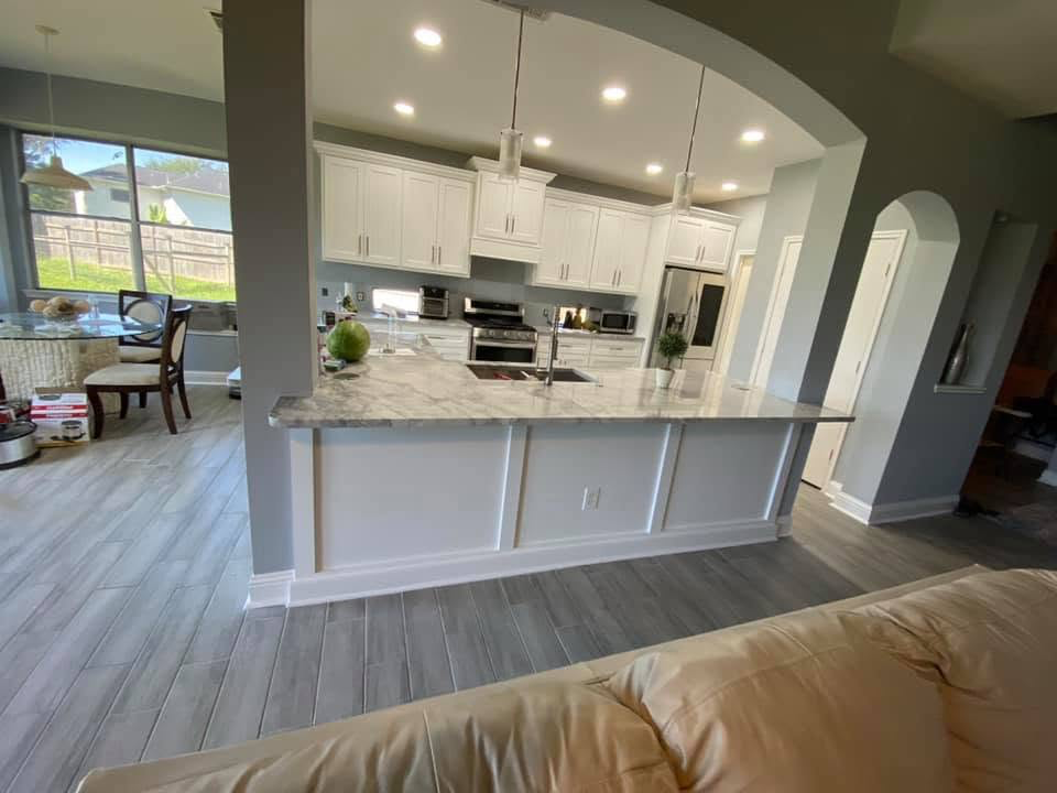 White kitchen with marble island bar Open-concept white kitchen with marble waterfall island bar and archway detail in Richmond TX