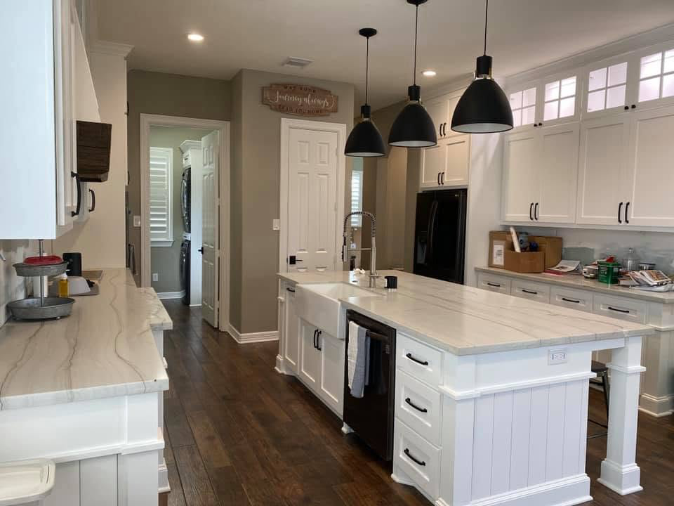 Farmhouse kitchen with apron sink Farmhouse kitchen remodel with apron sink, quartzite counters, and black pendant lighting in Fort Bend County TX